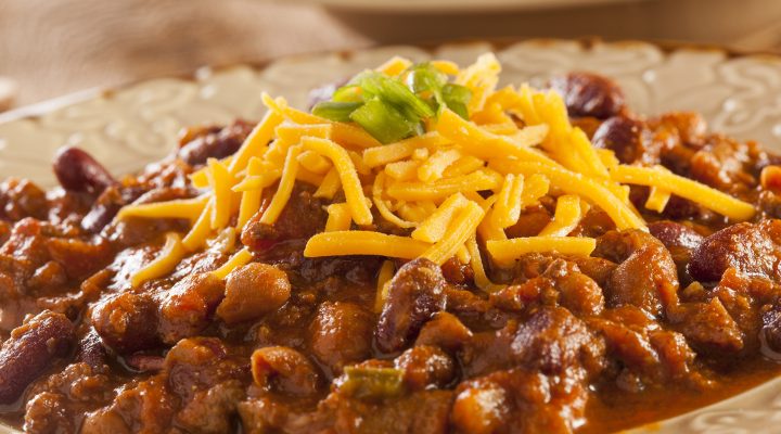 a close up of a bowl of slow cooker hearty bean, beef and sausage chili