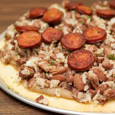 a close up of a red beans and rice with andouille pizza