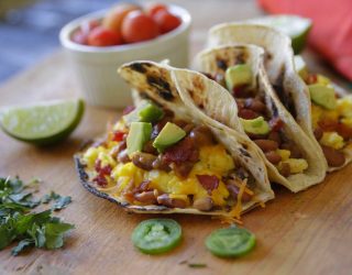 3 bacon and bean breakfast tacos on a cut board