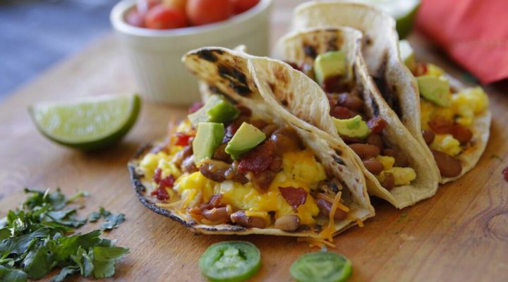 3 bacon and bean breakfast tacos on a cut board