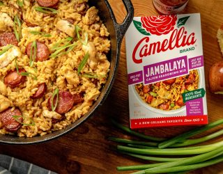 Cajun Jambalaya in a dutch oven featuring sausage and chicken next to a box of camellia brand jambalaya cajun seasoning mix