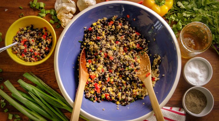 a mixing bowl filled with black bean quinoa salad waiting to be mixed