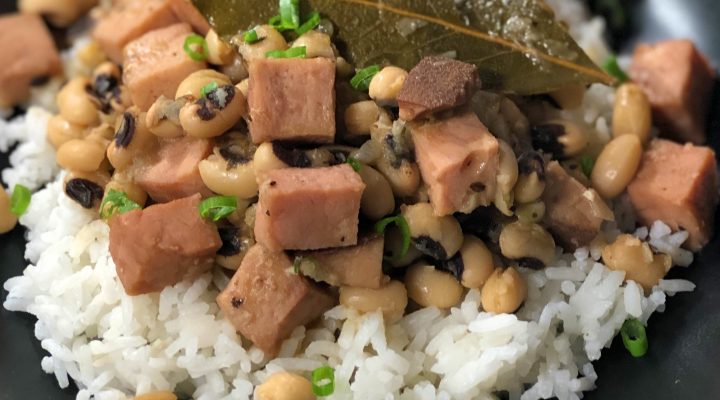 a close up of new years eve black eyed peas with ham chunks and a bayleaf