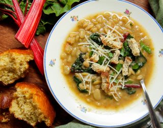 instant pot lima bean soup in a bowl with assorted greens and a side of bread