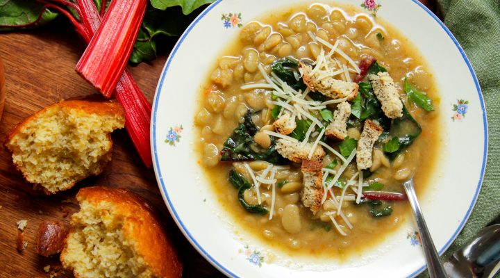 instant pot lima bean soup in a bowl with assorted greens and a side of bread