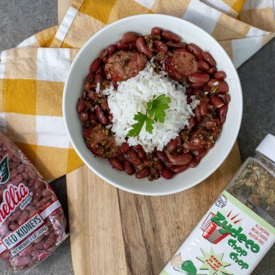 a bowl of red beans and rice next to a package of red beans and a container of zydeco chop chop seasoning