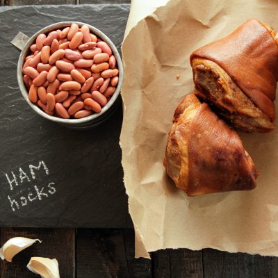 hamhocks and a cup of red beans on a charcoal cut board