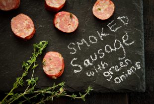 pieces of smoked sausge with green onions on a table with smoked sausage and green onions written on it