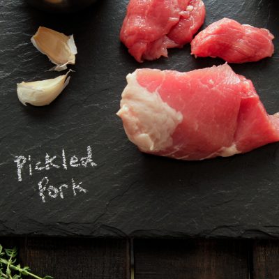 a piece of pickled pork on a charcoal cutting board with the text pickled pork written in chalk