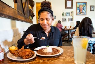 smile customer eating red beans and rice with a side of chicken and corn bread at willie mae