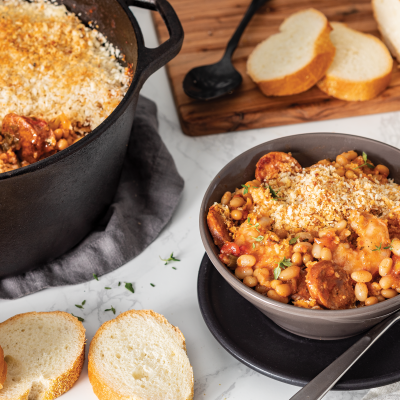 a bowl of Camellia's Shrimp, Andouille and White Bean Cassoulet next to a dutch oven