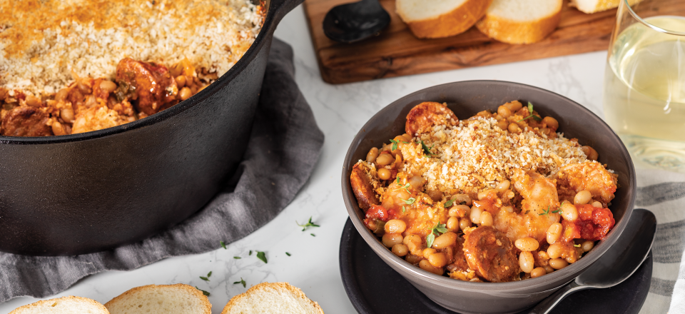 a bowl of Camellia's Shrimp, Andouille and White Bean Cassoulet next to a dutch oven