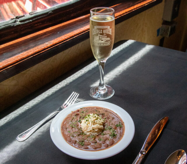 a bowl of red beans and rice and a glass of champagne from creole queen