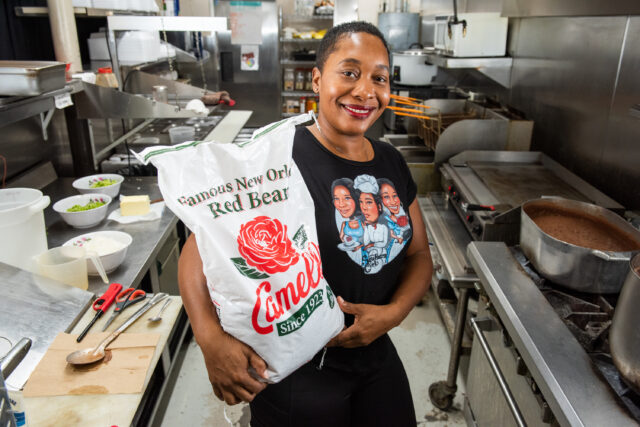 Owner of 3 Southern Girls smiling in the kitchen holding a large bag of Camellia Brand red beans